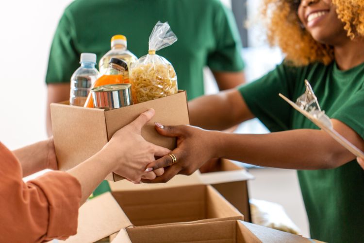 Mãos de pessoas segurando caixas com alimentos para doação