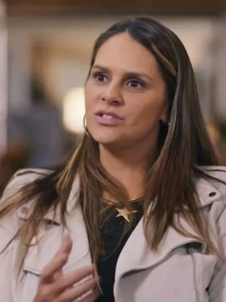 Print de entrevista de Shanna Garcia, que usa blusa preta e casaco bege