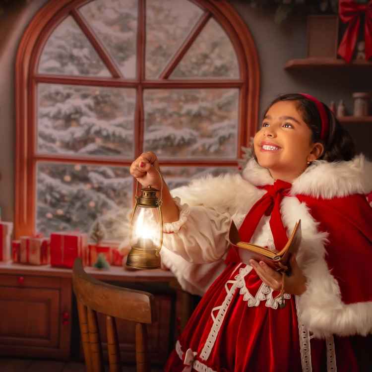 Menina sorridente, vestida com capa vermelha e branca, segura uma lanterna e um livro. Ela está em um ambiente natalino aconchegante, com janela mostrando neve e presentes ao fundo. A iluminação suave destaca a expressão de encantamento da criança.