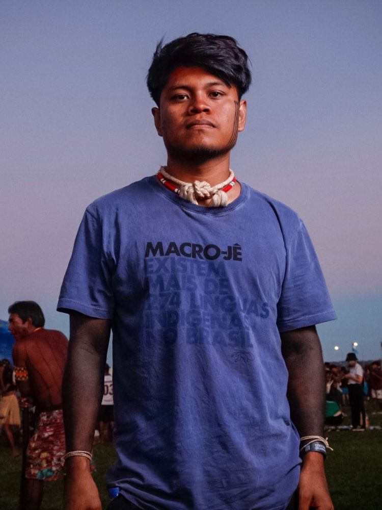 Cristian Wariu usando colares e camiseta azul com escritos