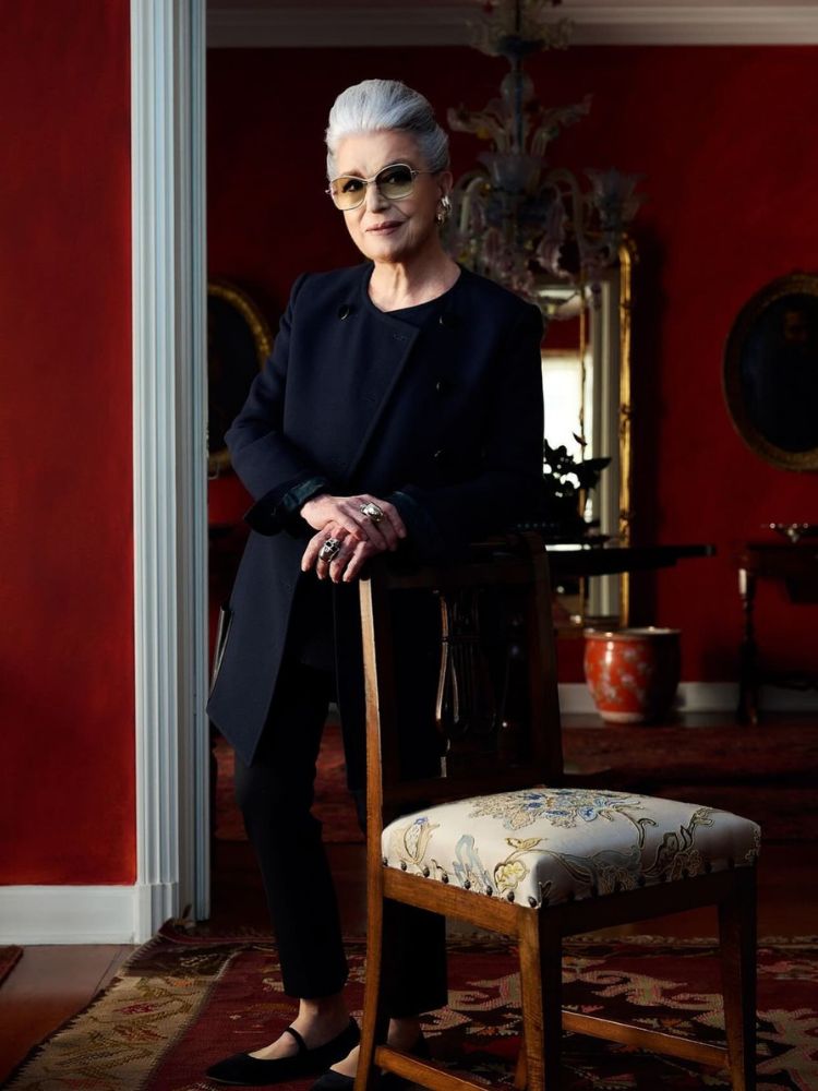Costanza Pacolato usando look all black, apoiada em encosto da cadeira
