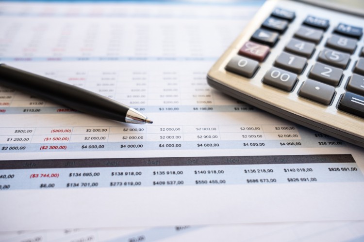 Foto de lista com valores, caneta e calculadora