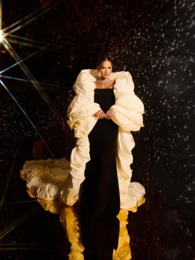 Foto da influenciadora usando vestido longo preto e casaco branco