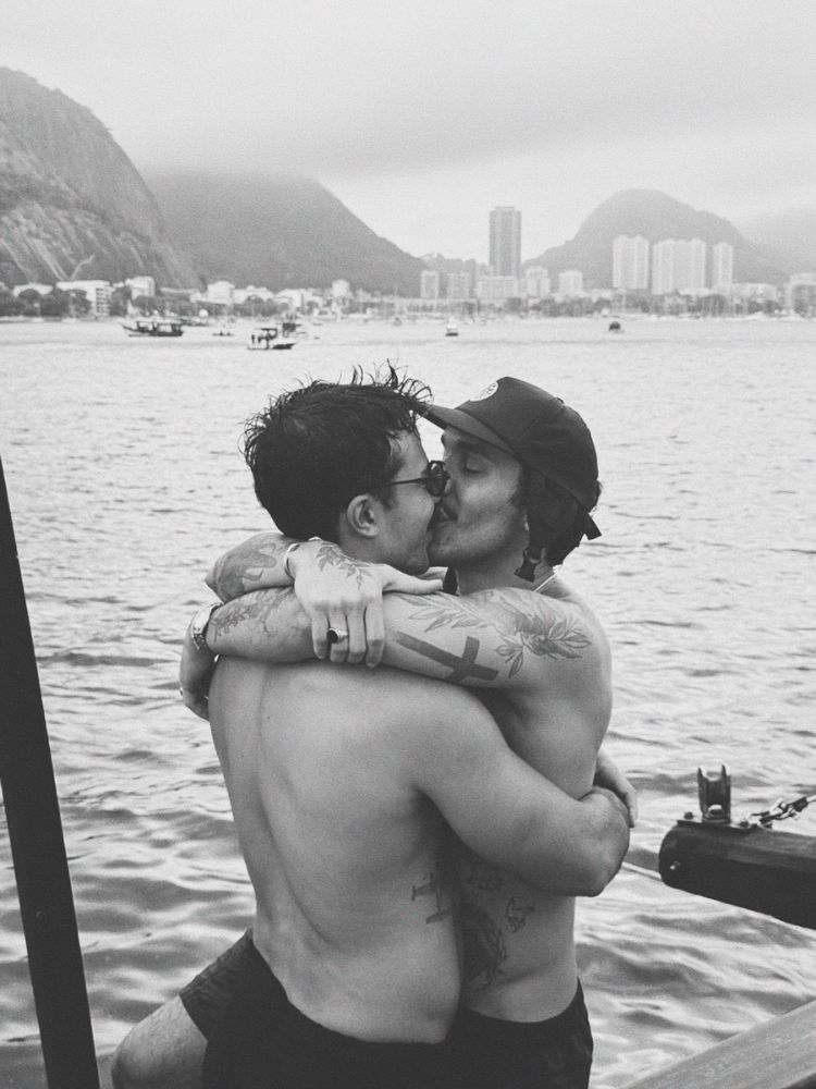 Foto em preto e branco de Mateus beijando homem de pele clara no mar