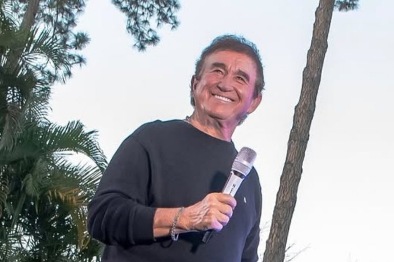 Foto de Amado Batista com camiseta preta segurando microfone