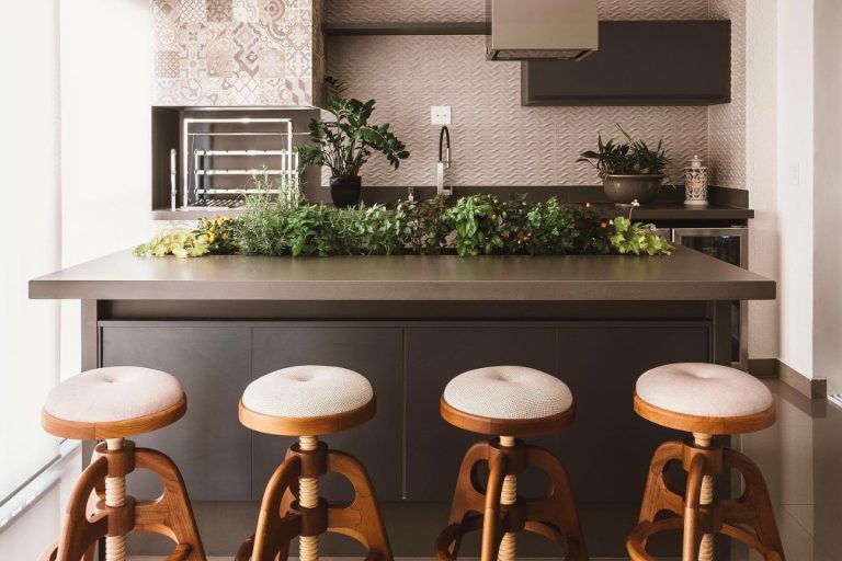 Área gourmet em apartamento com horta embutida na ilha, banquetas claras e pia ao fundo