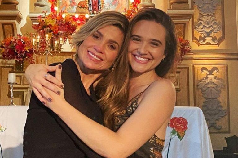 Flávia Alessandra e Juliana Paiva, atrizes, abraçadas e sentadas.
