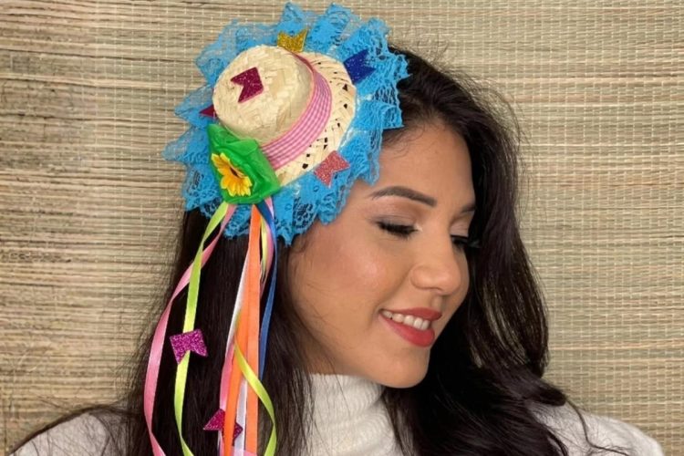 Mulher morena usando tiara de festa junina com aplicação de chapéu de palha e fitas de cetim