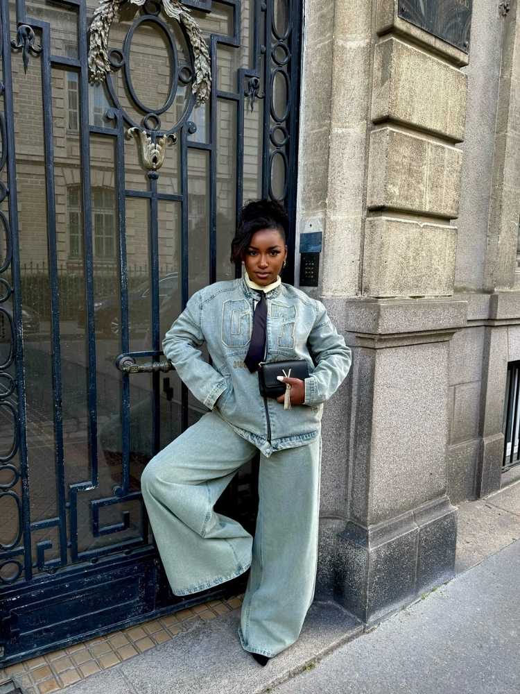 Mulher de pele negra de look all jeans e gravata preta