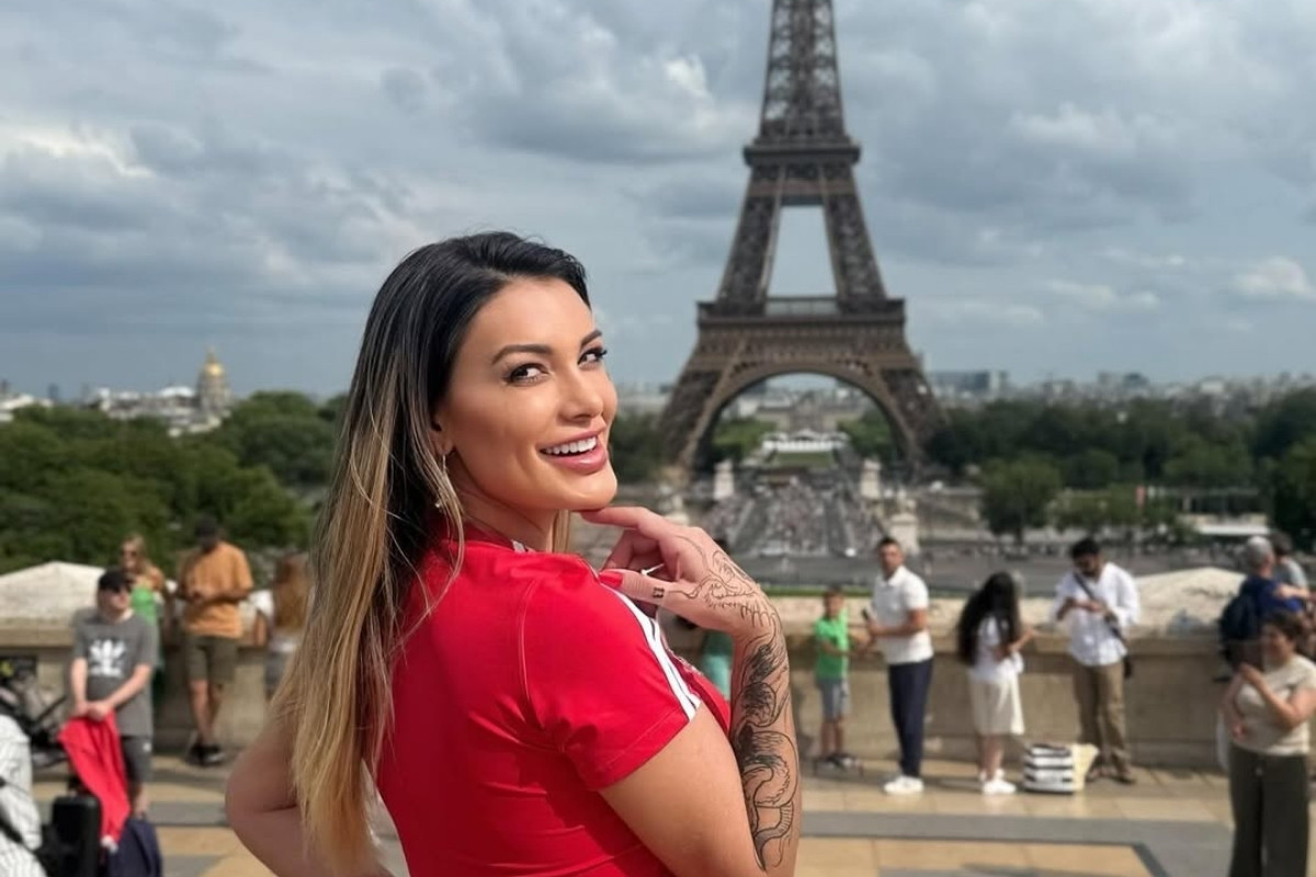 Foto da influenciadora Andressa Urach usando camiseta vermelha em frente à Torre Eiffel