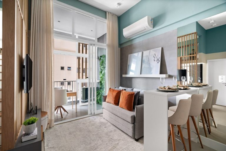 Apartamento com sala em verde e cinza, móvel de madeira, bancada com duas cadeiras