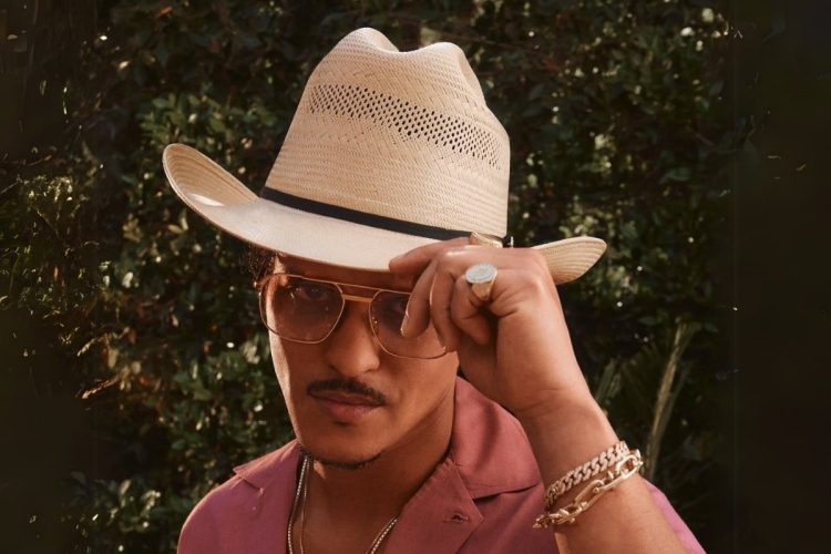 Foto de Bruno Mars usando chapéu de palha e camisa rosa