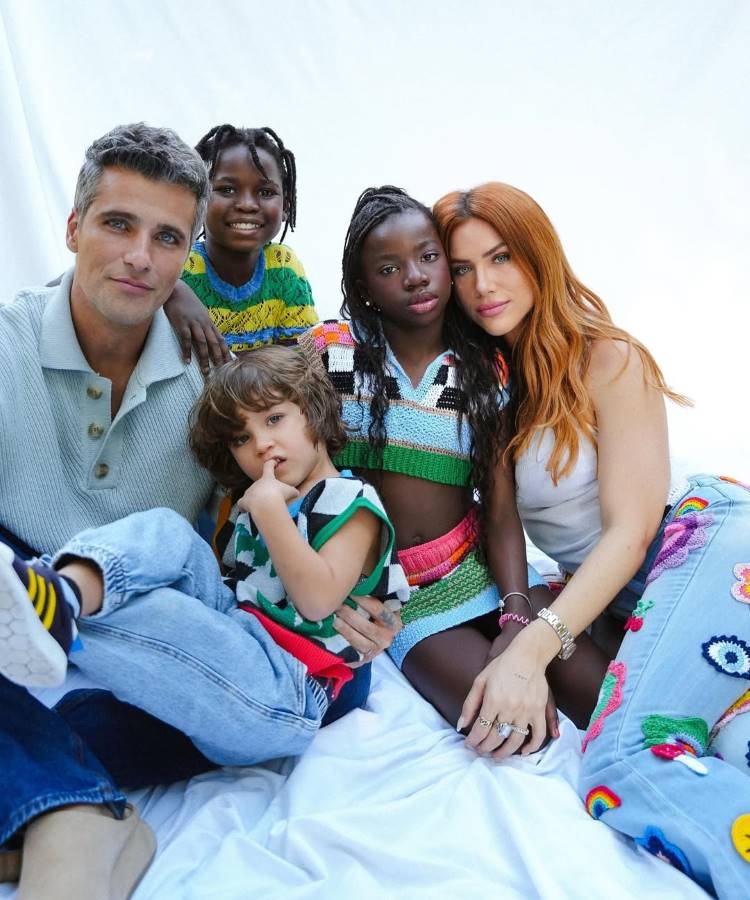 Casais famosos que reataram: A imagem mostra Bruno Gagliasso e Giovanna Ewbank com seus filhos Titi, Bless e Zyan. A família está sentada em um lençol branco, com as crianças em primeiro plano, exibindo roupas coloridas e estilosas.