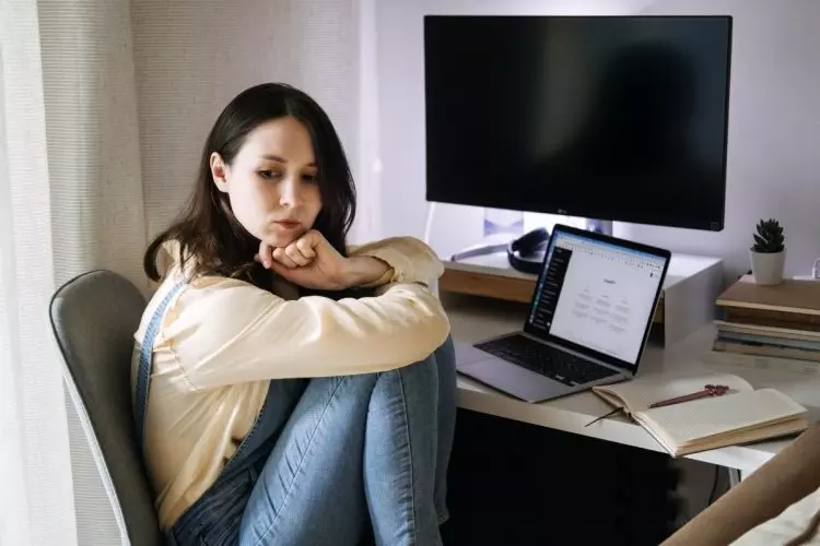 Foto de mulher triste em frente ao computador porque o ChatGPT caiu