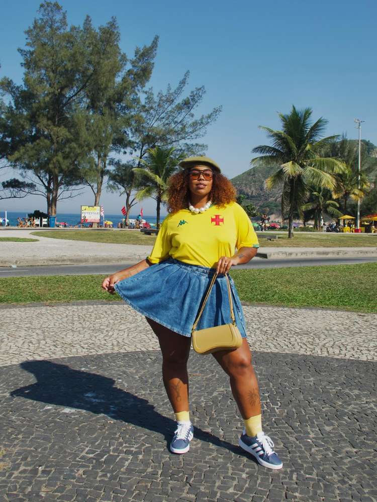 Mari Lobo com camisa do Vasco amarela e saia jeas na praia