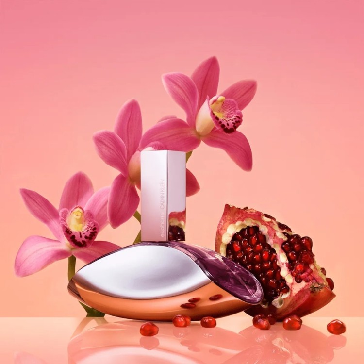 Fundo rosa, flores, romã e frasco de Euphoria, da Clavin Klein