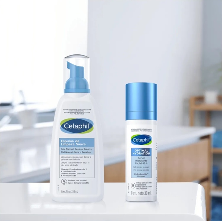A imagem exibe dois produtos Cetaphil: uma espuma de limpeza suave de 236ml, ideal como sabonete para pele sensível, e um sérum hidratante facial Optimal Hydration de 30ml. Ambos os frascos brancos com detalhes azuis estão sobre uma superfície branca, com foco na hidratação e cuidado da pele.