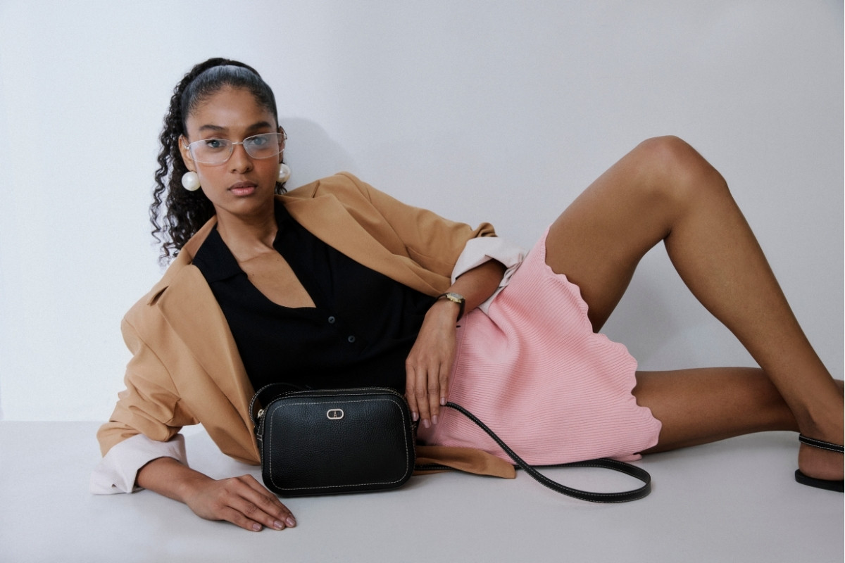 Modelo usando camisa preta, blazer cáqui, saia rosa e bolsa da linha Office da Anacapri