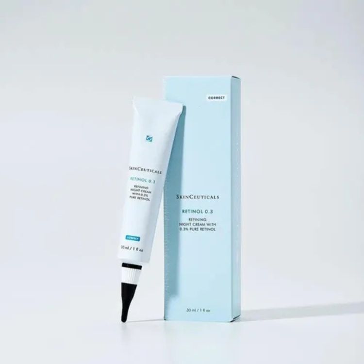 A imagem mostra um tubo e a caixa do SkinCeuticals Retinol 0.3, um creme noturno refinador com 0,3% de retinol puro. O tubo é branco com detalhes em azul e preto, e a caixa é azul-claro. Ambos indicam um volume de 30ml ou 1fl oz.