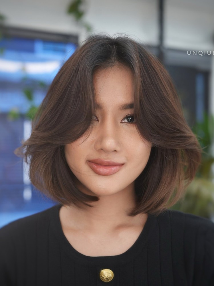 Mulher de origem asiática com cabelo castanho curto ocm curtain bangs