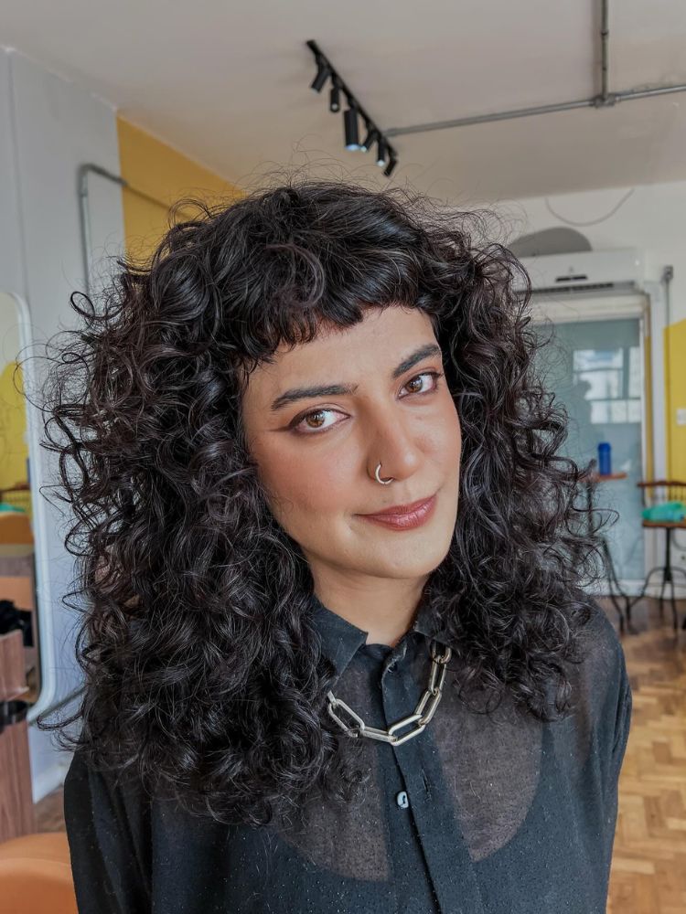 Mulher de pele clara com shaggy hair volumoso, cacheado e castanho 