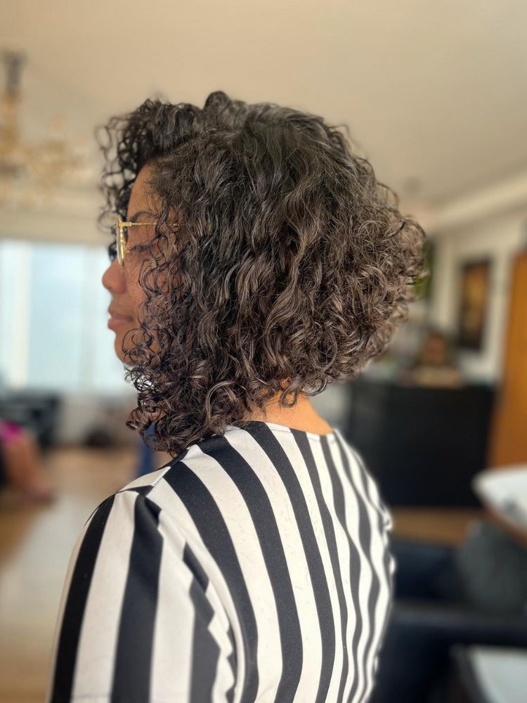 Mulher d epele morena com chanel de bico castanho e cacheado 