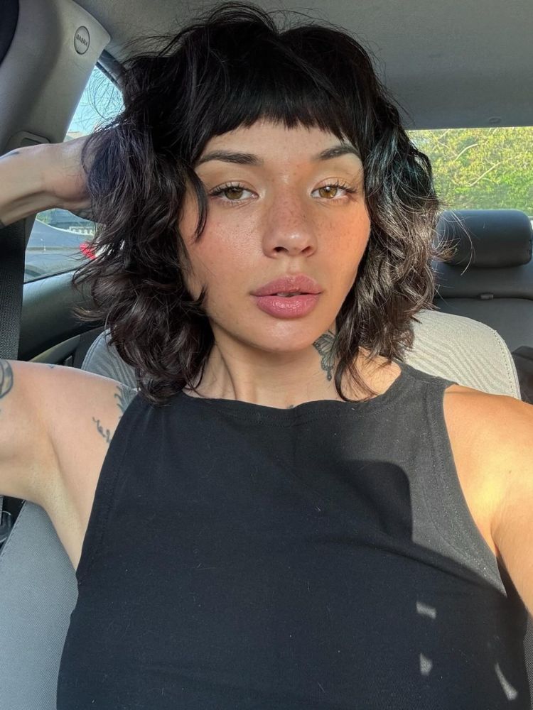 Mulher de pele morena no carro com cabelo castanho french bob