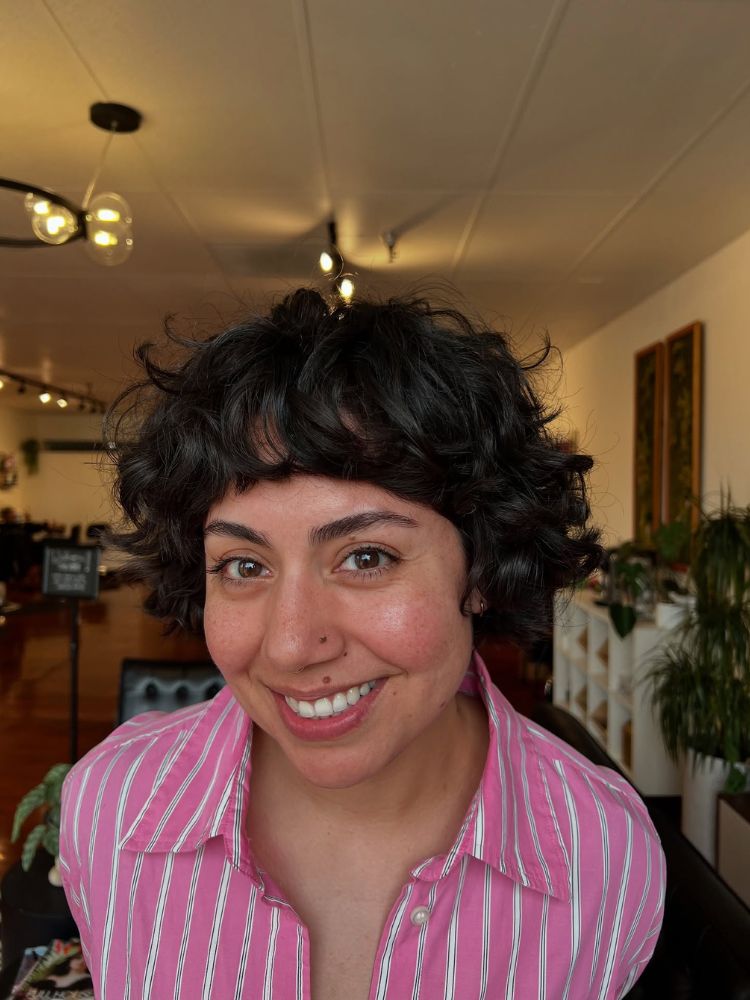 Mulher de pele clara com cabelo cacheado castanho em french bob