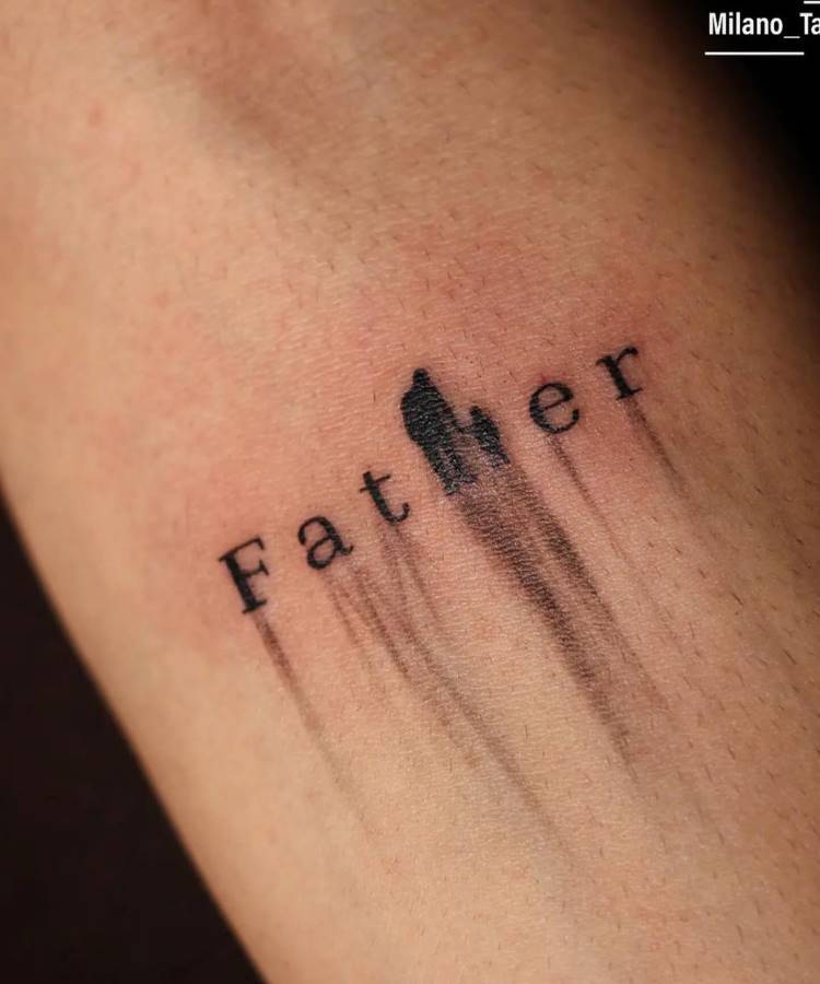 Uma tatuagem minimalista no antebraço de um homem. A palavra "Father" está escrita, com a letra "h" substituída pela silhueta de um pai e um filho. Um efeito borrado em preto se estende para baixo da silhueta, adicionando movimento ao design.
