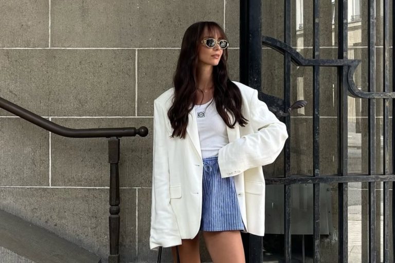 Foto de mulher morena de cabelos longos usando óculos de sol, regata branca, blazer de linho e tendência de shorts para o verão 2026