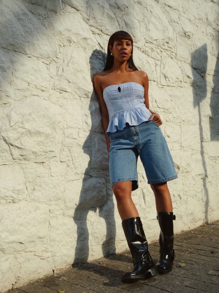 Larissa Cunegundes de cropped azum claro sem manga, bermuda jeans e bota 