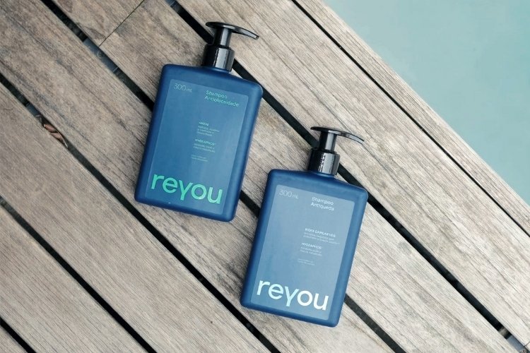 Foto de dois shampoos da marca reyou® em deck ao lado de piscina