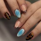 Foto de unhas decoradas que são tendências para 2026: azul claro e animal print