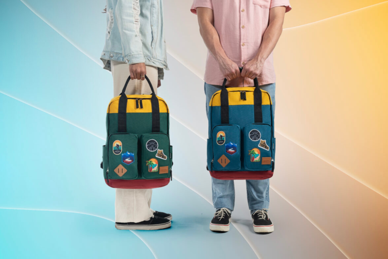 Duas pessoas segurando mochilas coloridas inspiradas na lojinha do Big Brother Brasil