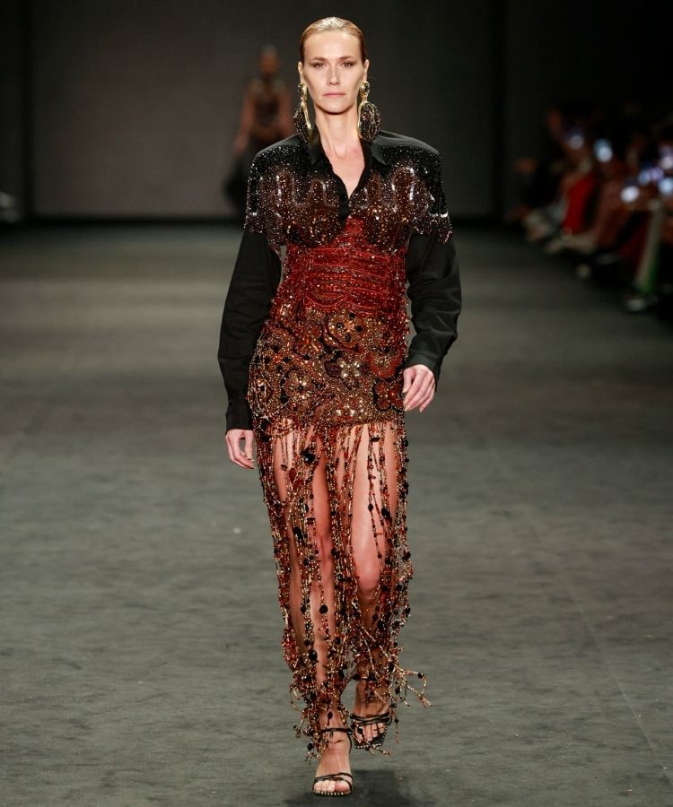 Modelo na passarela usando look com miçangas, uma das tendências do Rio Fashion Week 2026
