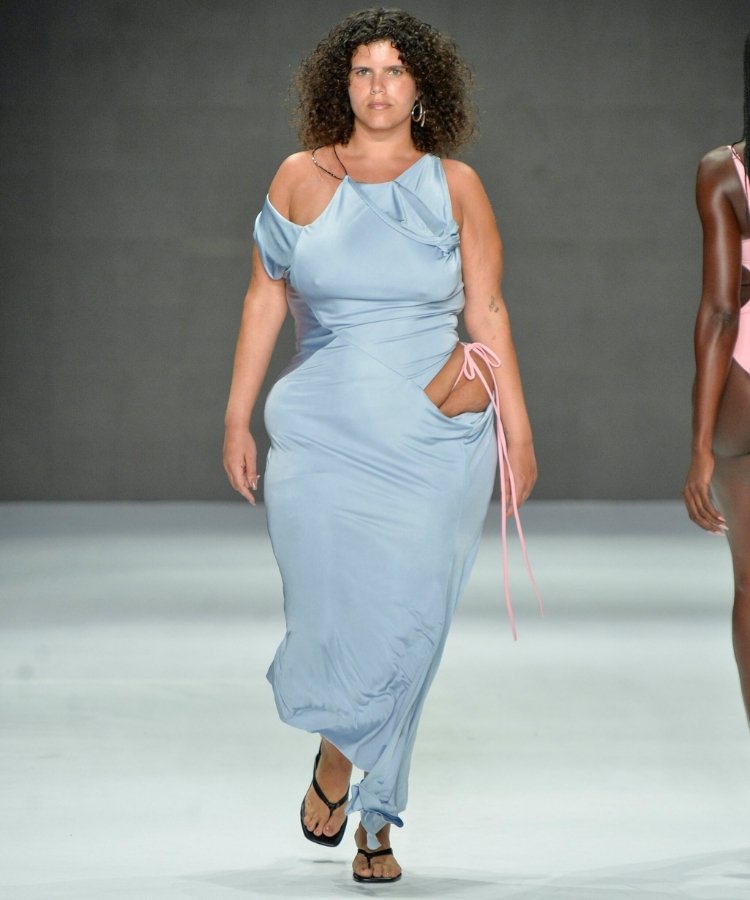 Modelo na passarela usando vestido azul com recorte estratégico, uma das tendências do Rio Fashion Week 2026