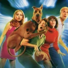 Turma do Scooby-Doo em versão live-action reunida durante investigação sobrenatural em cenário iluminado.