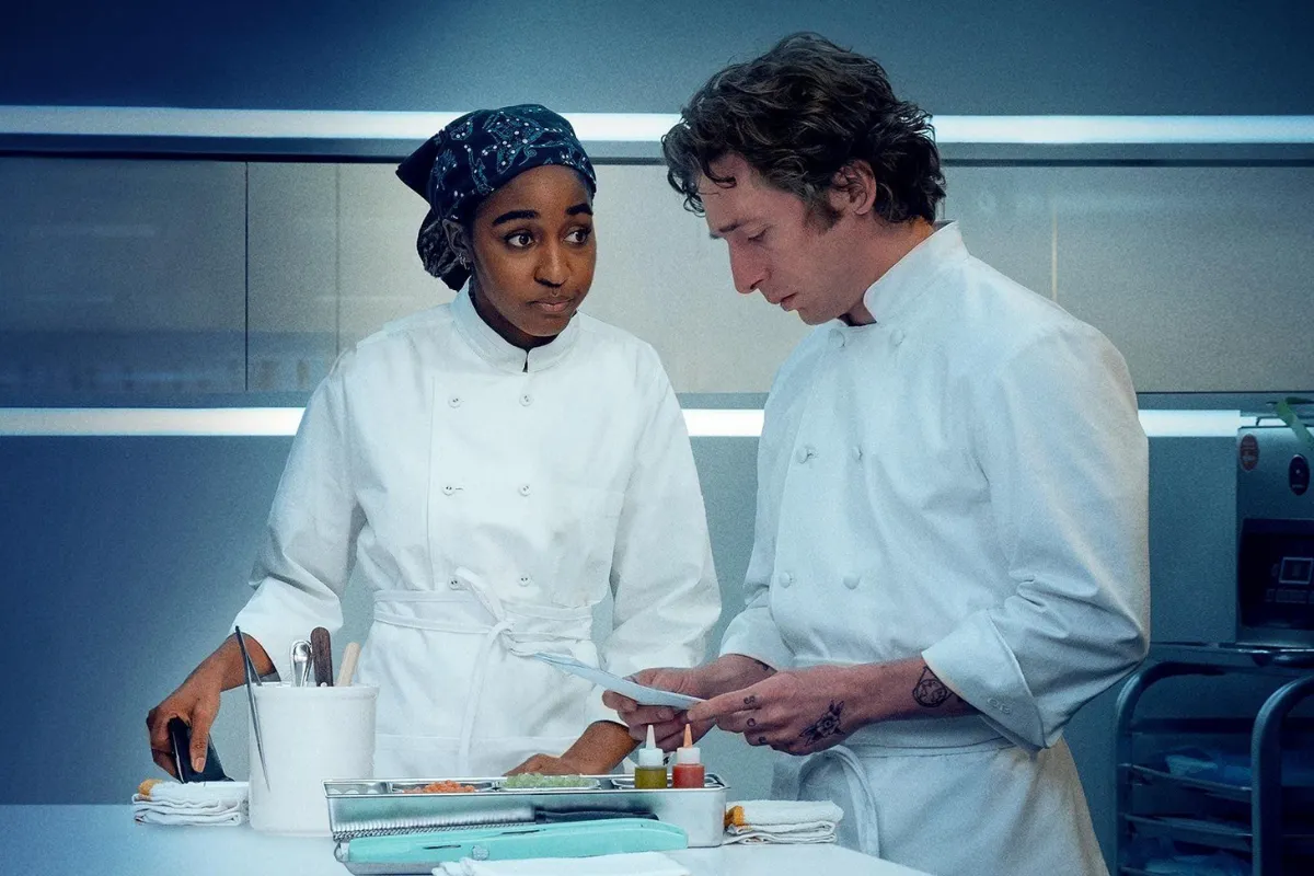 Personagens da série The Bear analisam pratos em cozinha industrial iluminada na Disney+ em 2026.