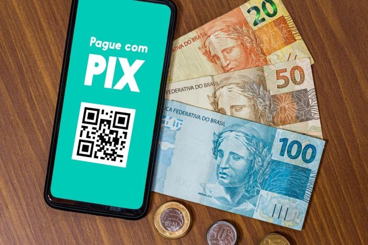 Celular com cédulas de dinheiro realizando Pix para apostas online