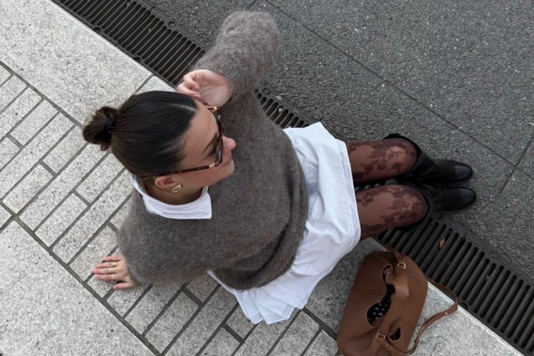 Foto de influencer usando look com meia-calça estampada, vestido branco, suéter cinza e bota preta