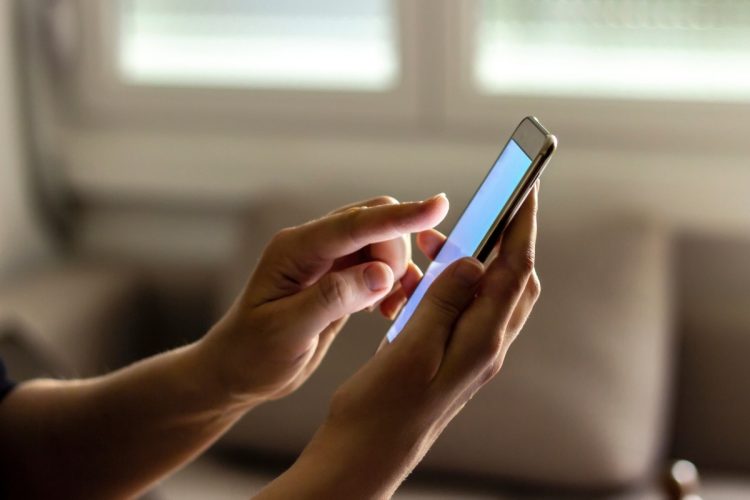Mão de pessoa mexendo no celular para fazer escolha das plataformas de apostas online