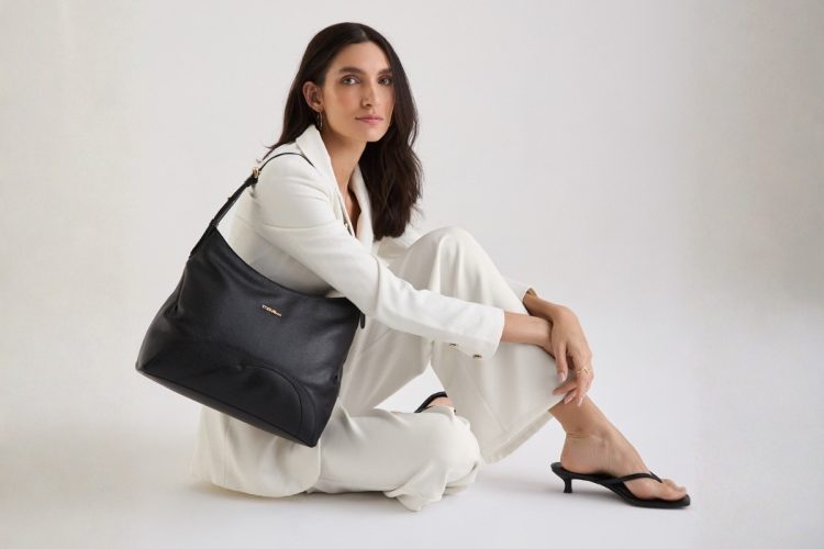 Modelo usando look branco e segurando bolsa de couro média preta da Move & Co