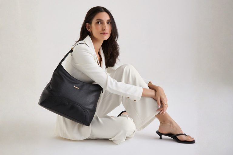 Modelo usando look branco e segurando bolsa de couro média preta da Move & Co