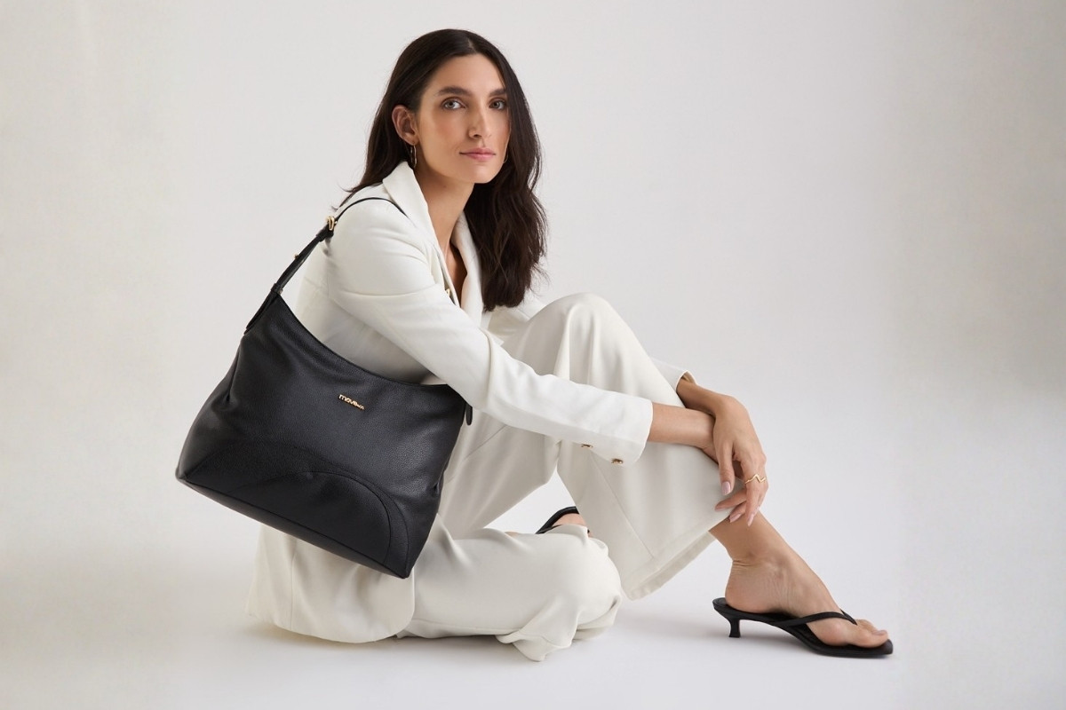 Modelo usando look branco e segurando bolsa de couro média preta da Move & Co